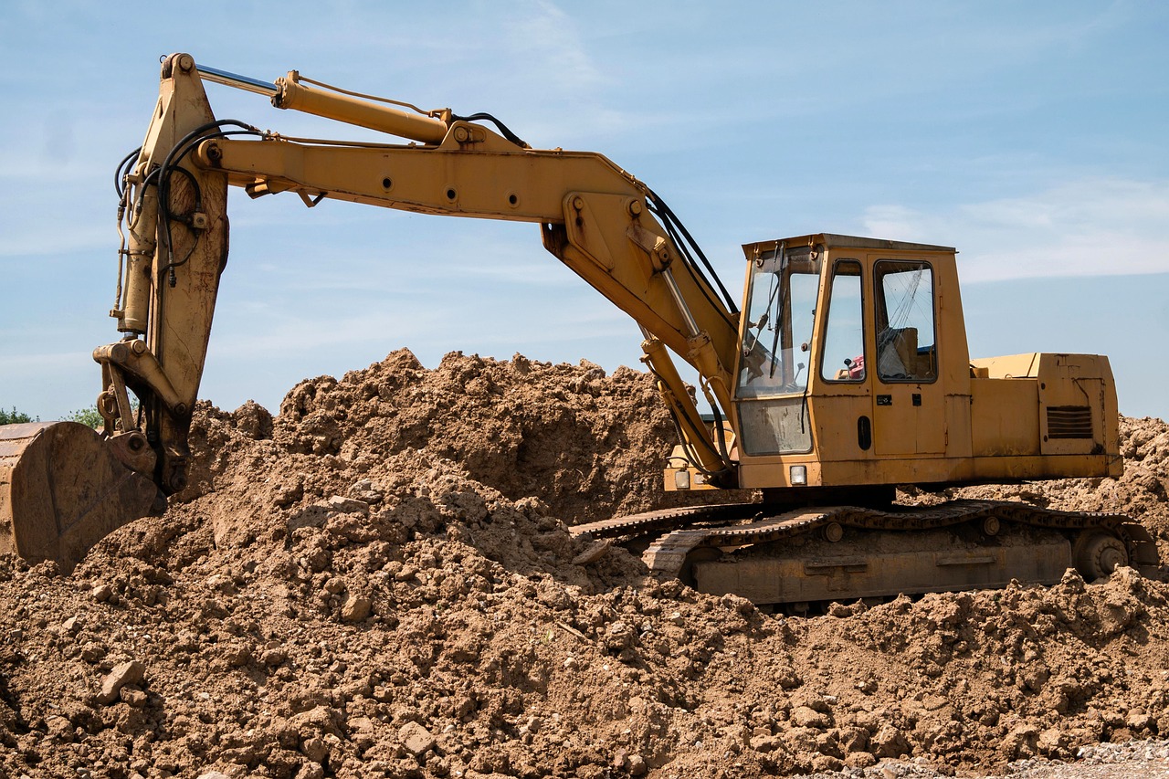 An excavator on top of a dirt pile.