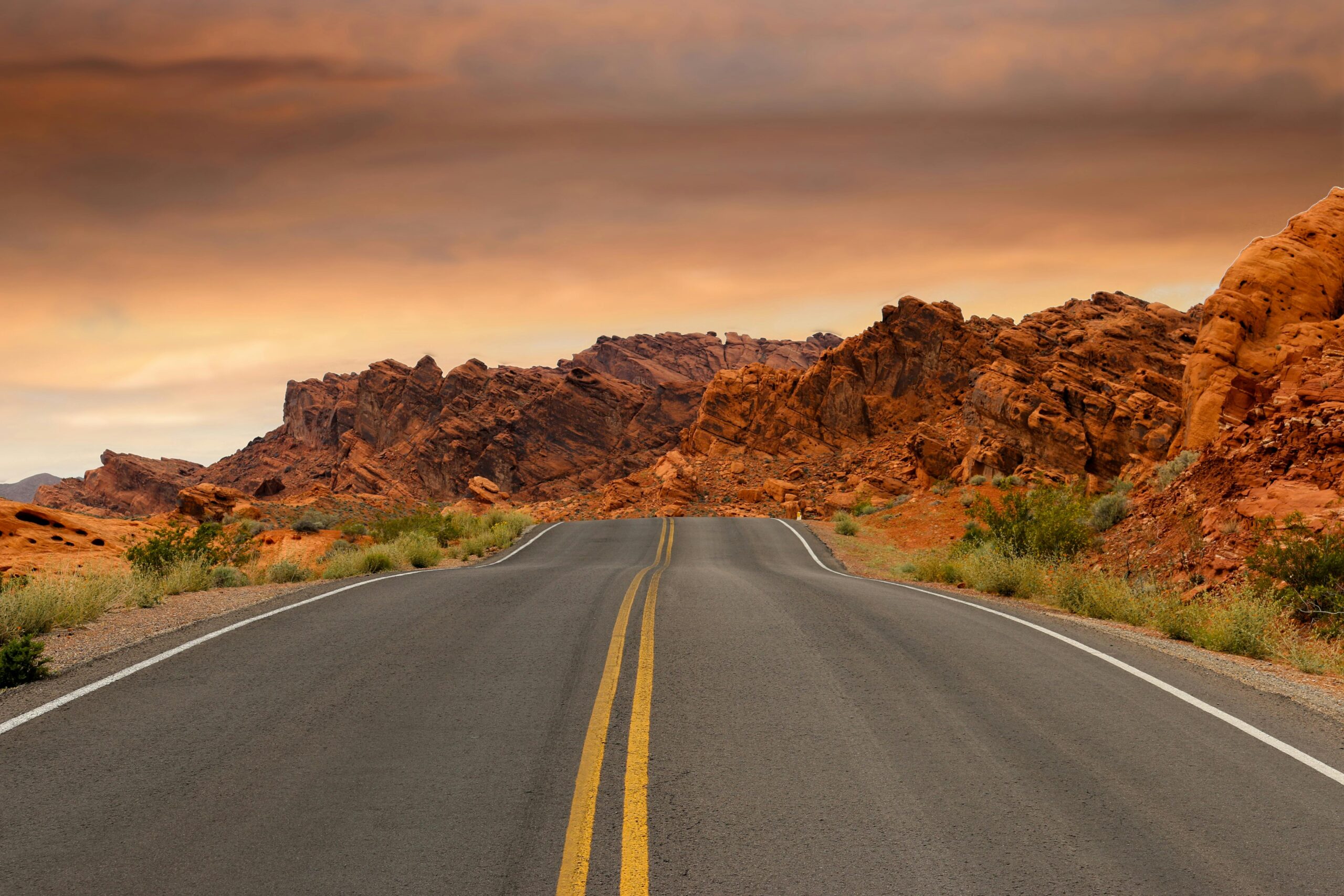 A highway leads to red rocks in the distance on an American highway.