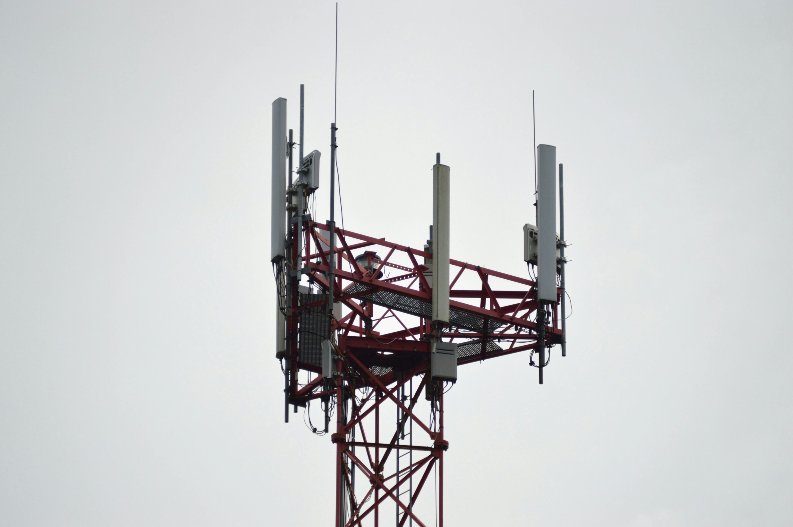 A 5G tower connecting residents and businesses to broadband internet service before a white cloudy sky.