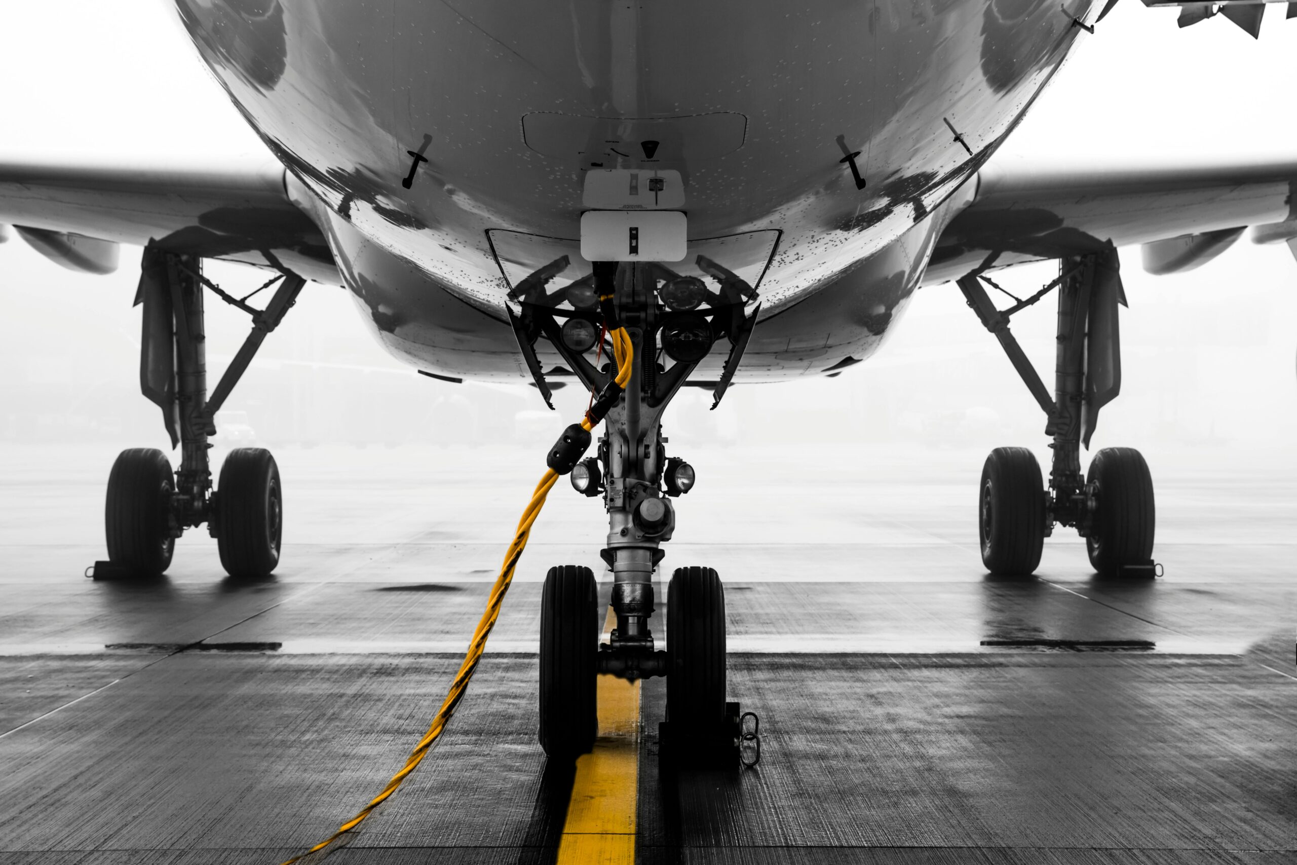 The landing gear and the belly of an airplane on the tarmac.