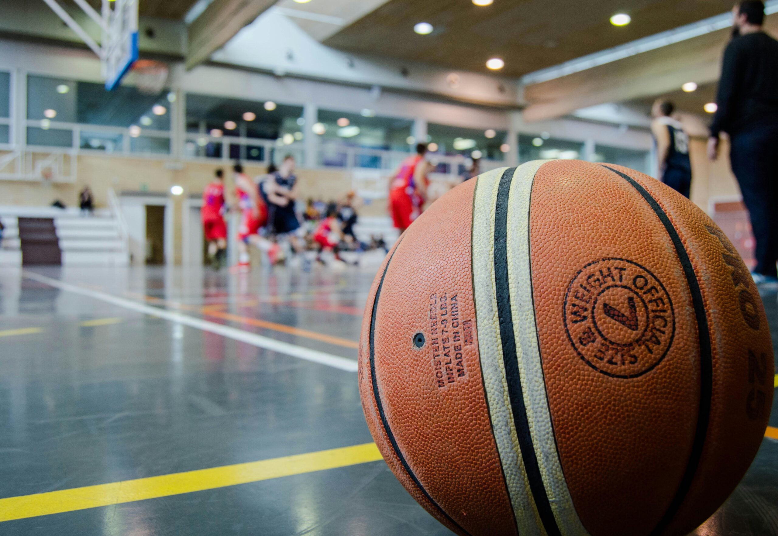 A basketball in an arena before players on the court.