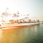 A freightliner waits at a port in the water.