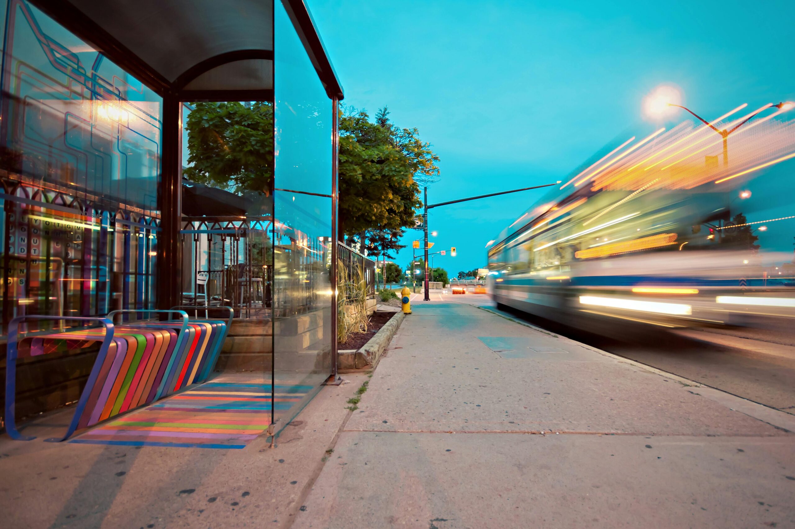 denver-bus-rapid-transit-project A bus zooms past a bus station with a multi-colored bench.