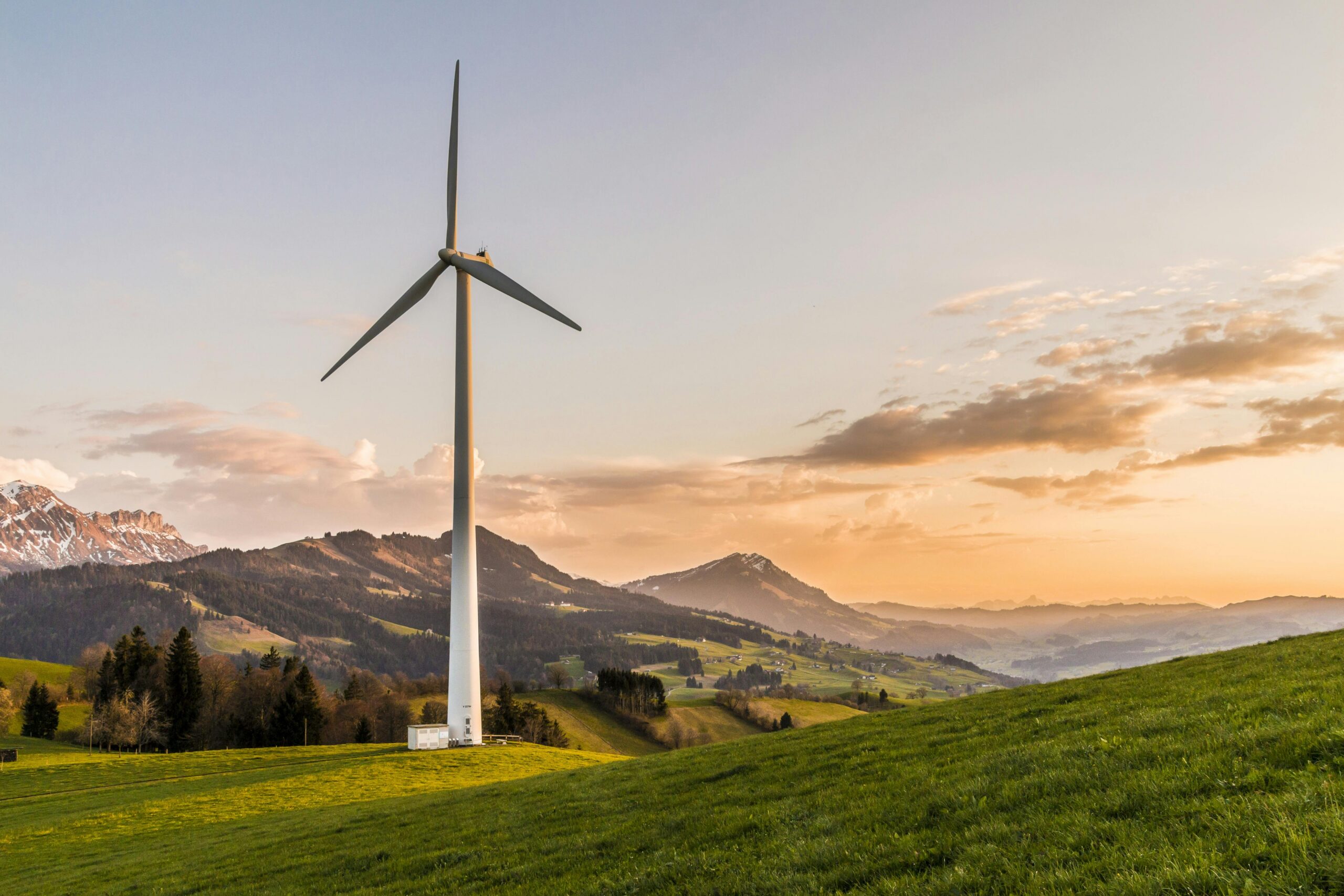 california-cpuc-energy-push A white windmill before a setting sun and rolling hills.