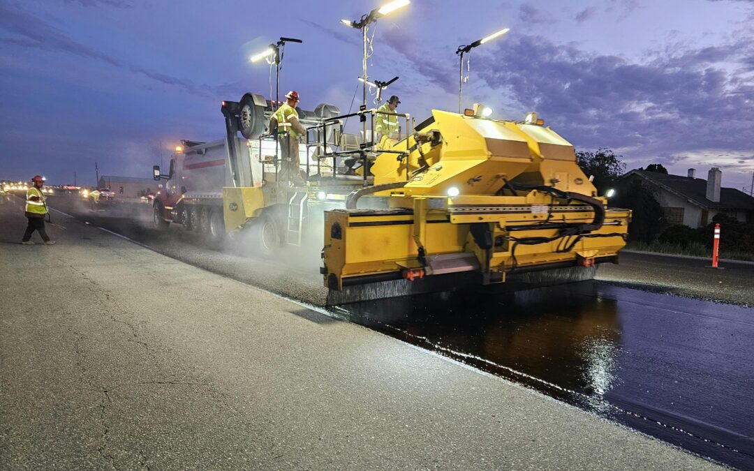 A road paving machine working on a road during the nighttime.