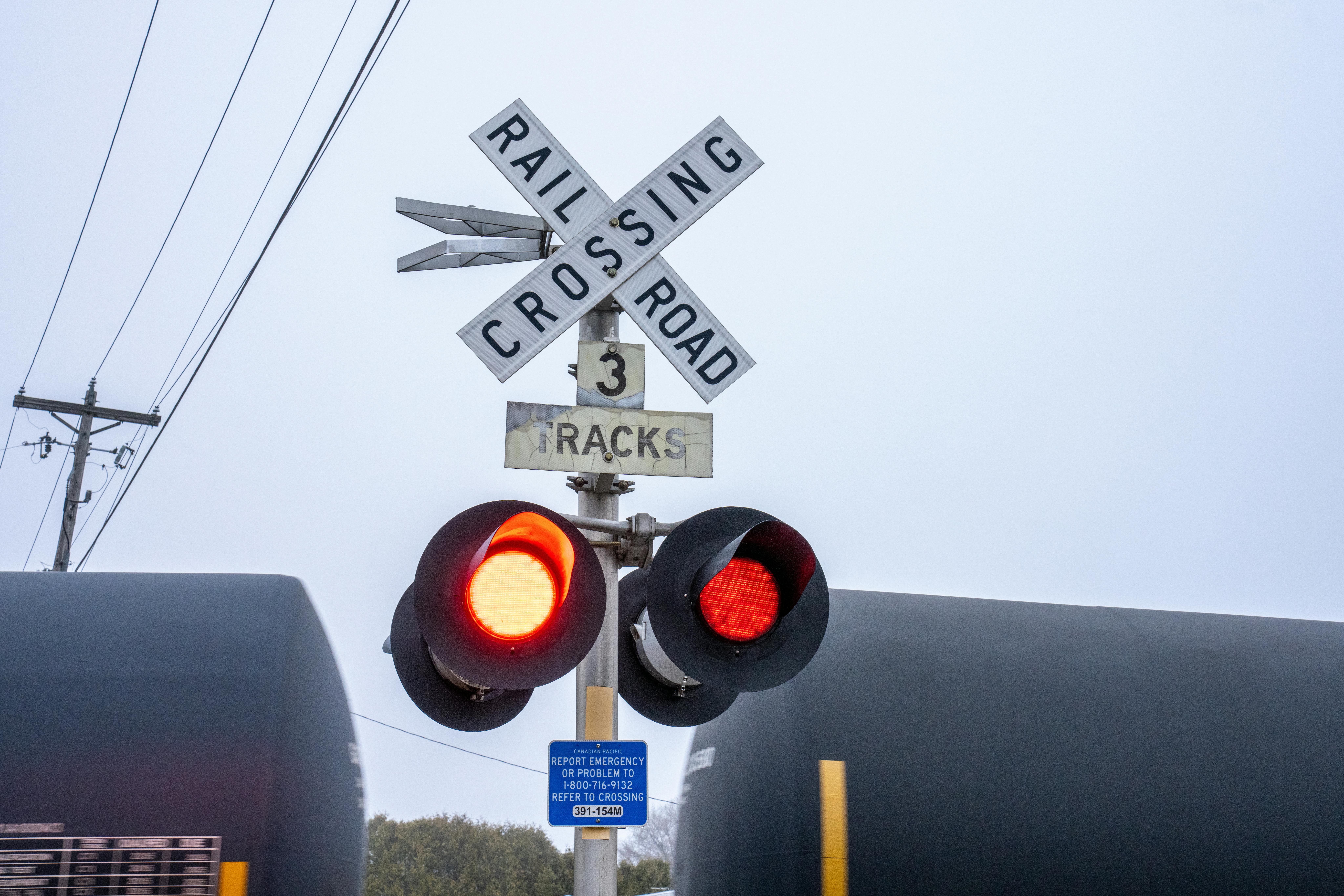 illinonis-rail-crossing A rail crossing sign before a moving train carrying oil tankers.